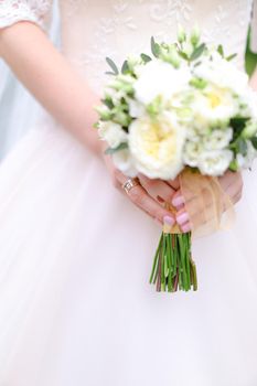 Closeup bride hands keeping white bouquet. Concept of wedding photo session.