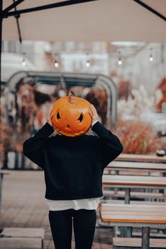 Girl with a pumpkin head posing on the street . Halloween Concept