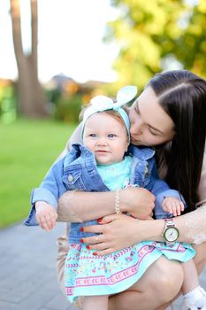 Young woman holding little daughter wearing jeans jacket. Concept of motherhood and children.