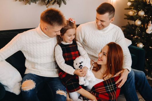 Close-up portrait of a happy family sitting on a sofa near a Christmas tree celebrating a holiday.