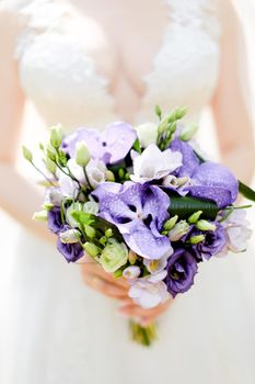 Closeup bridal bouquet of violet flowers. Concept of wedding photo session and floristic art.