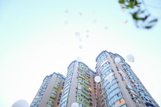 High building and flying white balloons in background. Concept of celebrating success.