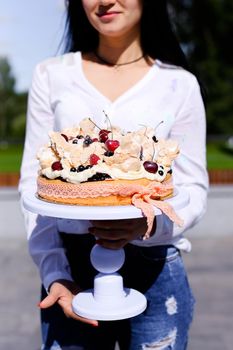Smiling woman wearing white blouse keeping birthday cake. Concept of sweets and tasty food for party.