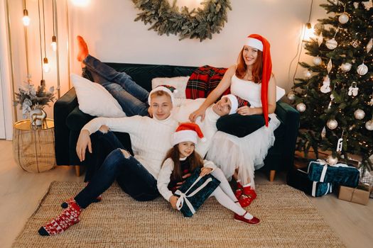 Close-up portrait of a happy family sitting on a sofa near a Christmas tree celebrating a holiday.