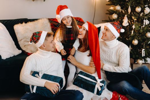 Close-up portrait of a happy family sitting on a sofa near a Christmas tree celebrating a holiday.