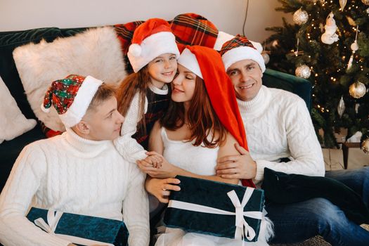 Close-up portrait of a happy family sitting on a sofa near a Christmas tree celebrating a holiday.