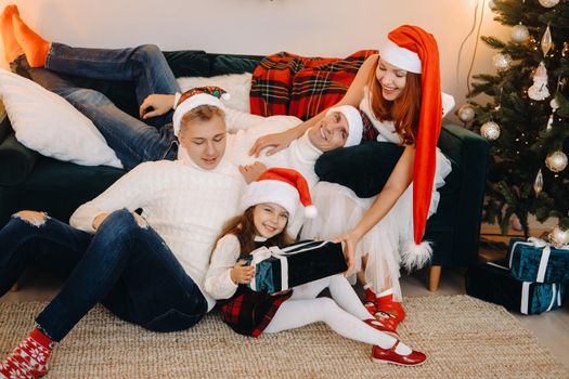 Close-up portrait of a happy family sitting on a sofa near a Christmas tree celebrating a holiday.