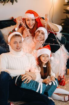 Close-up portrait of a happy family sitting on a sofa near a Christmas tree celebrating a holiday.