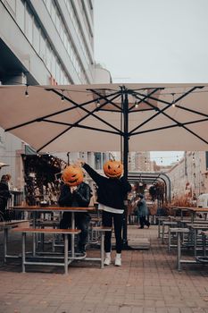 Guy and girl with pumpkin heads in a street cafe. Halloween Concept
