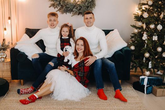 Close-up portrait of a happy family sitting on a sofa near a Christmas tree celebrating a holiday.