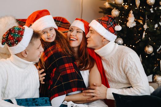 Close-up portrait of a happy family sitting on a sofa near a Christmas tree celebrating a holiday.