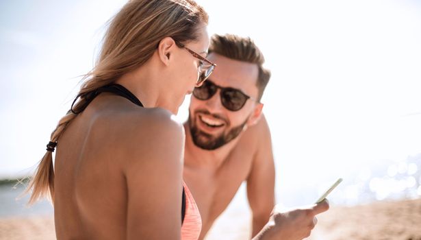 Romantic couple browsing their photos on the beach