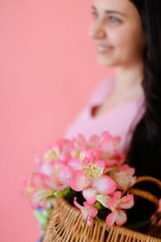 Young girl and focus on flowers in pink monophonic background. Concept of flora and photo session at studio.