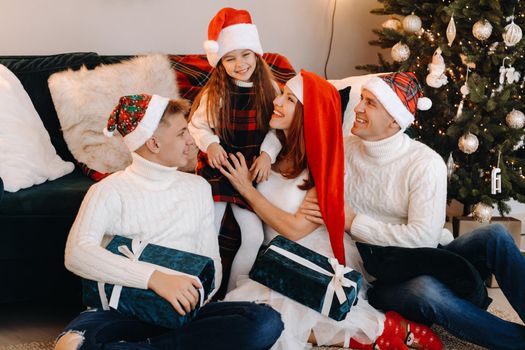 Close-up portrait of a happy family sitting on a sofa near a Christmas tree celebrating a holiday.