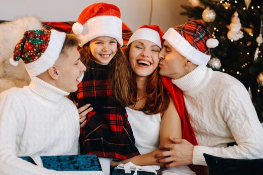 Close-up portrait of a happy family sitting on a sofa near a Christmas tree celebrating a holiday.