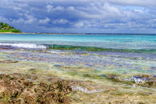 The view from the shore of a beautiful tropical sea with a beach. The warm waters of the ocean bathe colorful stones in the water. Vacation concept.