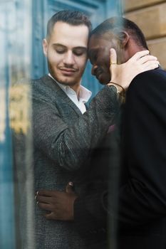 Reflection in window of two kissing boys, afro american and caucasian. Concept of gays and lgbt.