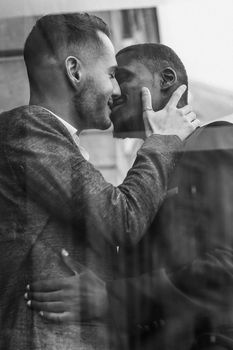 Black and white bw portrait Reflection in window of two kissing boys, afro american and caucasian. Concept of gays and lgbt in Paris