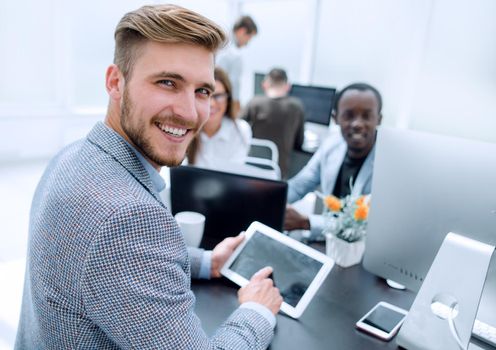 smiling businessman sitting at the office Desk.people and technology