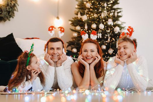 Close-up portrait of a happy family lying near a Christmas tree celebrating a holiday.