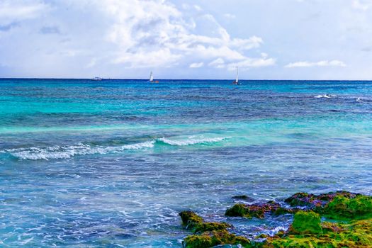 The view from the shore of a beautiful tropical sea with a beach. The warm waters of the ocean bathe colorful stones in the water. Vacation concept.