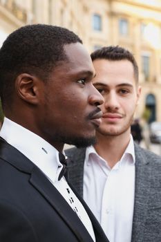 close up portrait of same sex couple. caucasian man wearing suit standing near afro american boy. Concept of business and male fashion.