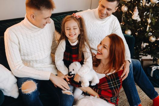 Close-up portrait of a happy family sitting on a sofa near a Christmas tree celebrating a holiday.