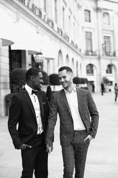 Black and white bw portrait Afro american and caucasian gays walking and speaking outside in city. Concept of same sex male couple in Paris