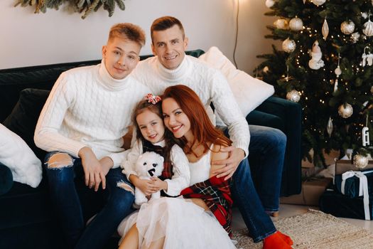 Close-up portrait of a happy family sitting on a sofa near a Christmas tree celebrating a holiday.