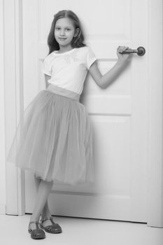 A nice little girl is standing by the door. The concept of family happiness and a home.