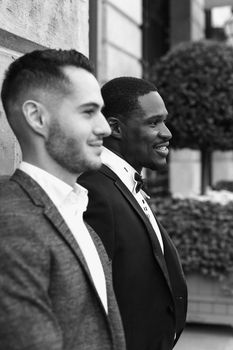 Black and white bw portrait Afro american and european gays standing near building and wearing suits. Concept of lgbt and walking in Paris