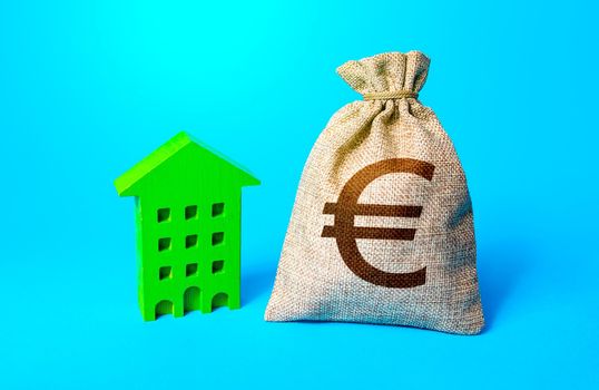 Euro money bag and green apartments house. Investments in sustainable housing. Investment in green technologies. Reducing impact on environment. Reduced emissions and improved energy efficiency.