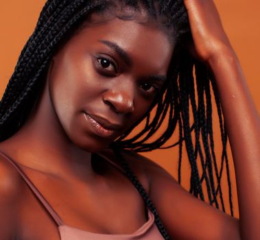 pretty young african american woman with braids posing cheerful gesturing on brown background, lifestyle people concept close up