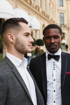 close up portrait of same sex couple. caucasian man wearing suit standing near afro american boy. Concept of business and male fashion.