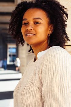 young pretty african girl posing cheerful on city background, lifestyle outdoor people concept close up