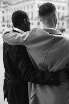 Black and white bw back portrait in Paris. Caucasian man running with afroamerican male person and holding hands in city. Concept of happy gays and strolling.