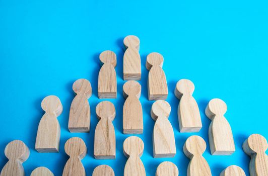 Wooden figures of people in one direction on a blue background. Social organizations, commercial structure. Organization, joining consolidated forces. Team building, teamwork cooperation. Discipline