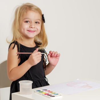 Little girl draws paints on a sheet of paper. Concept kindergarten, montessori education.