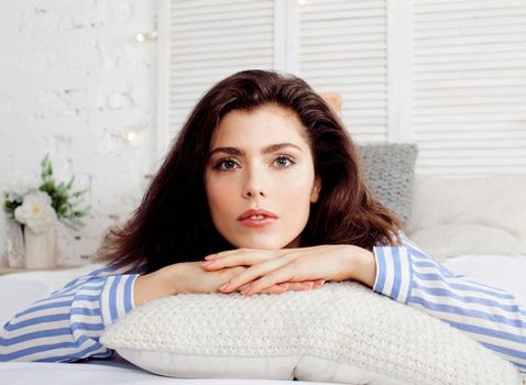 young pretty brunette woman in her bedroom sitting at window. lifestyle people concept