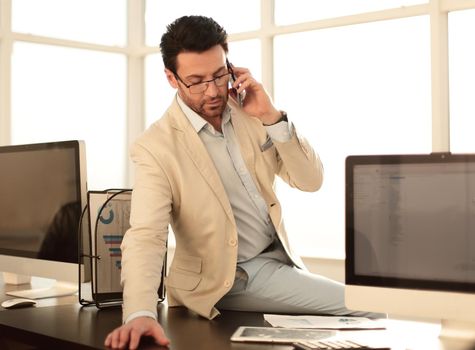 serious businessman talking on smartphone sitting on his desktop.business concept