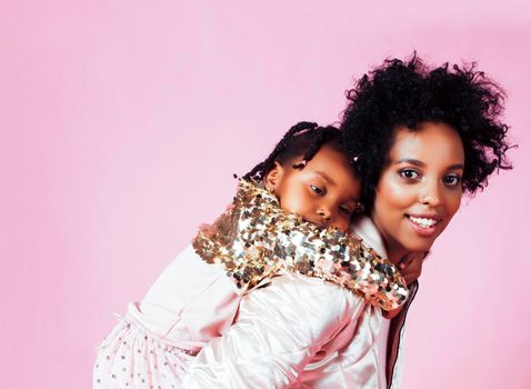 young pretty african-american mother with little cute daughter hugging, happy smiling on pink background, lifestyle modern people concept close up