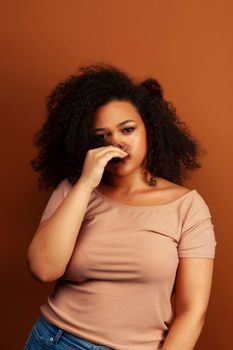 pretty young african american woman with curly hair posing cheerful gesturing on brown background, lifestyle people concept close up