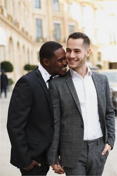 Afro american and caucasian stylish gays walking outside in city. Concept of same sex male couple.