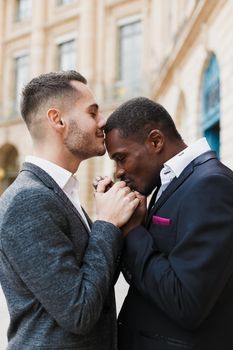 close up portrait of afro american guy kissing caucasian boy hands. Concept of same sex couple, gays and lgbt proposal