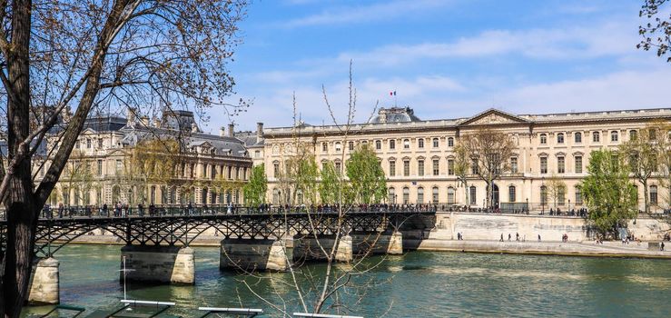 Pedestrian bridge (Pont des Arts) over Seine river and historic buildings of Paris France. April 2019