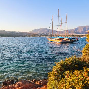 Beautiful Mediterranean coast with islands, mountains and yacht at sunset