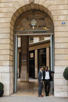 Two happy men, caucasian and afro american, wearing suits speaking near building outdoors. Concept of successful business partners.