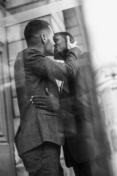 Black and white bw portrait Reflection in window of two kissing boys, afro american and caucasian. Concept of gays and lgbt in Paris
