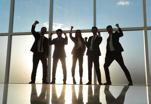 a team of professionals rejoices in a modern city office with a panoramic window.