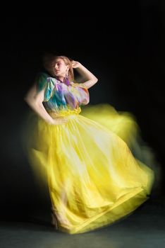 beautiful woman in long yellow dress posing dynamic in the studio